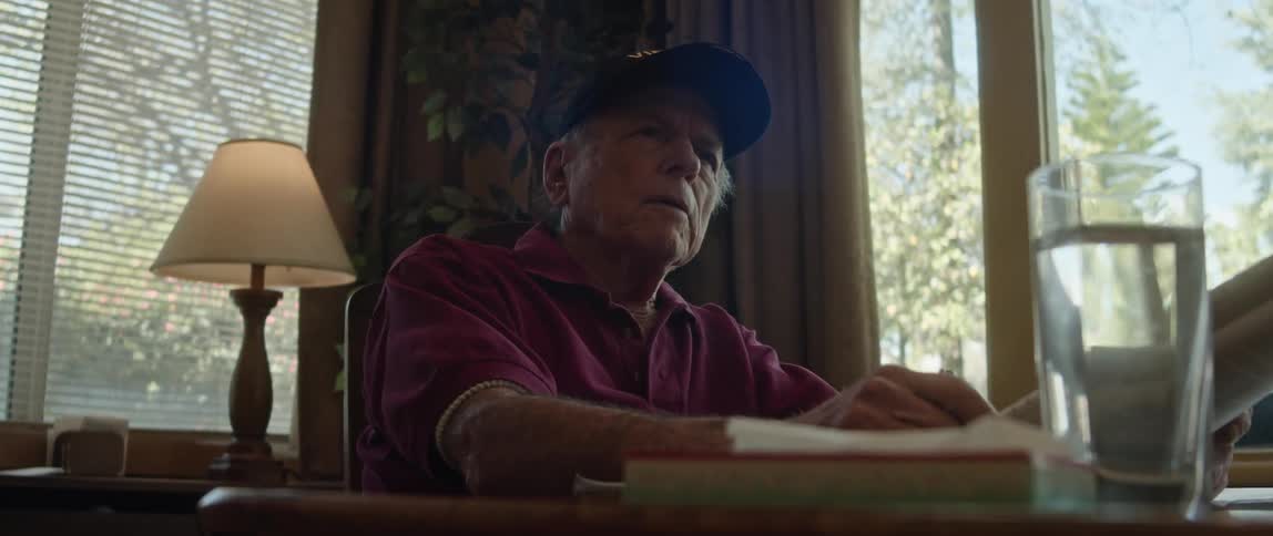 An elderly man is sitting down around the day time