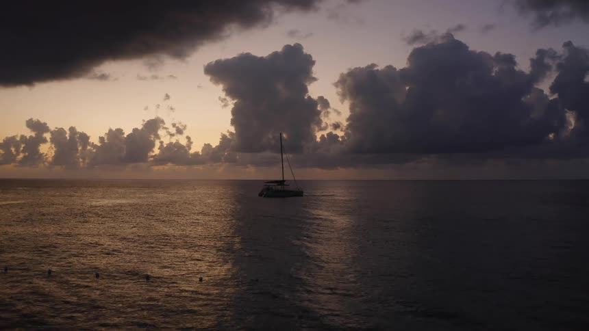 Silhouette of a sailboat floating on the calm ocean waters at evening