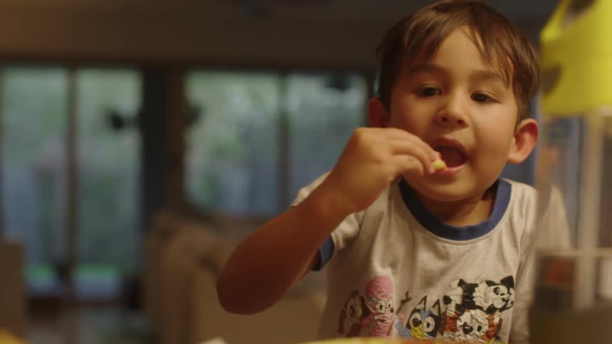 Boy with gray shirt dips food into a liquid and eats it