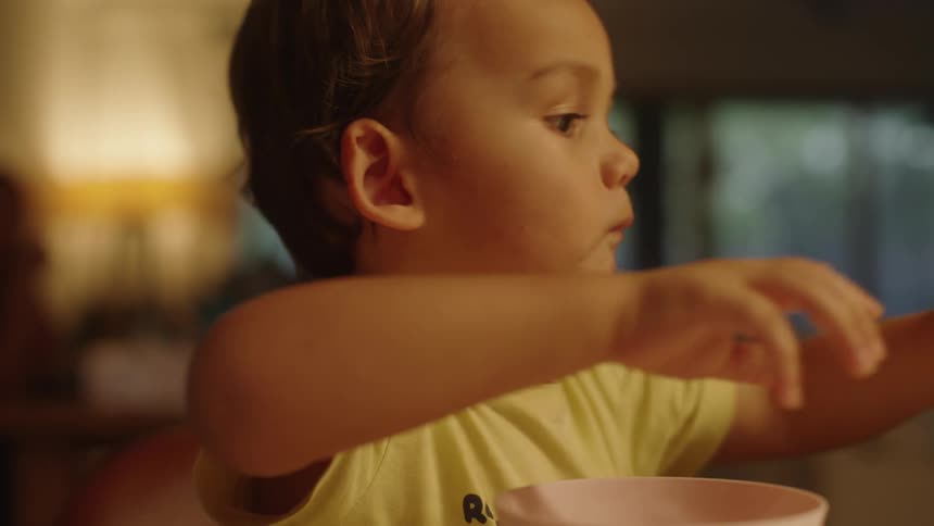 A close up of a young boy eating french fries in front of a bowl