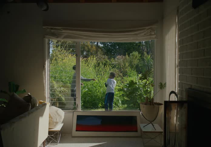 Brothers playing outside in front of plants while they hit each other with sticks