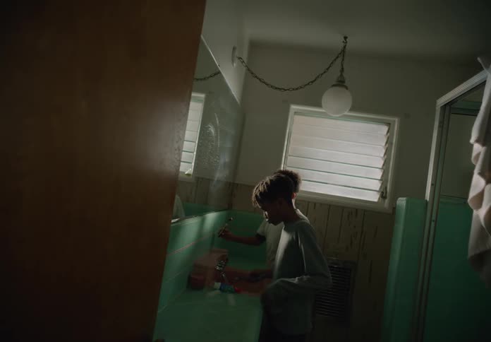 Two boys brushing their teeth in a bathroom and spitting in the sink