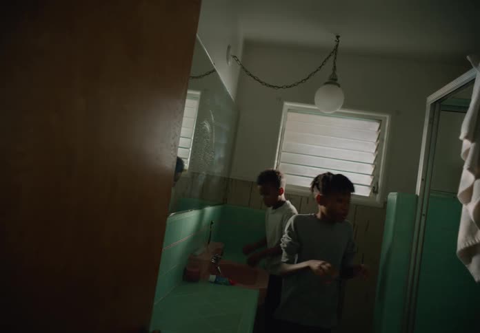 Brothers standing next to each other at the bathroom sink while they wash their faces