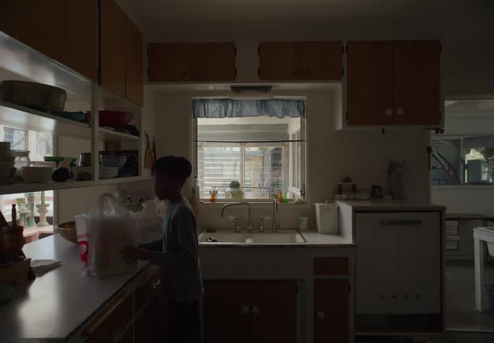 A child brings groceries into the kitchen and begins unpacking