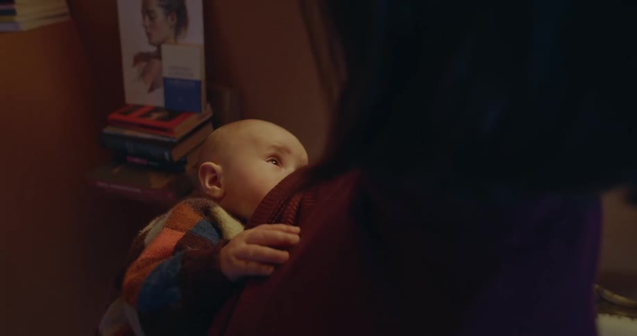 An small baby looks up at its mother while calmly breastfeeding