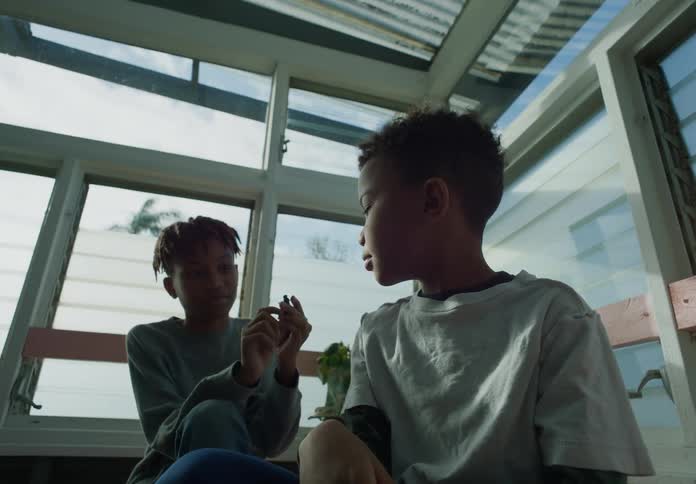 Two boys are sitting on a porch taking turns holding a little animal toy figure
