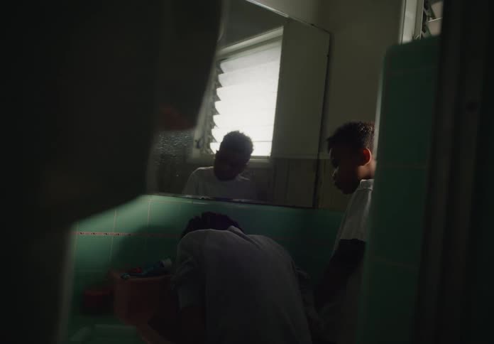 Two boys wash their faces in the bathroom sink
