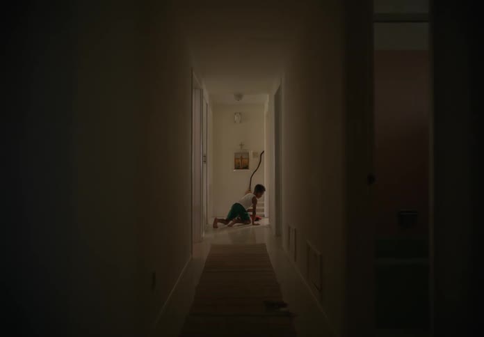 A boy runs down a hall and plays with a toy indoors