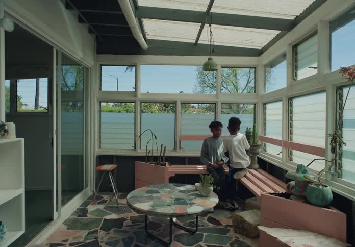 Two tween brothers in sunroompatio sitting in corner hanging out and playing