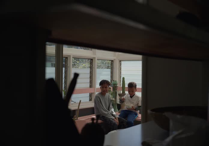Two young brothers sit on the bench in the balcony eating cereal