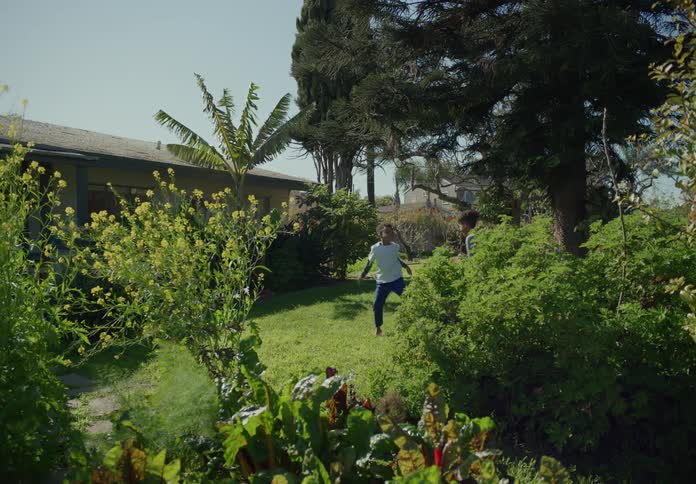Two boys run into the backyard garden and play