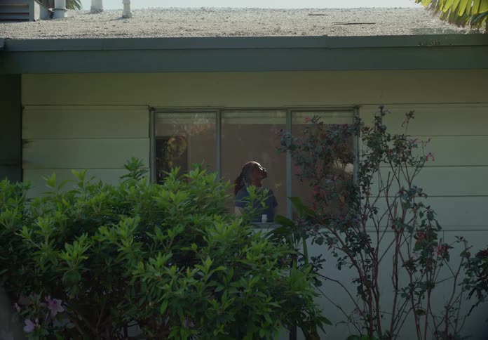 A woman standing inside her house in front of a window looking up and twisting side to side