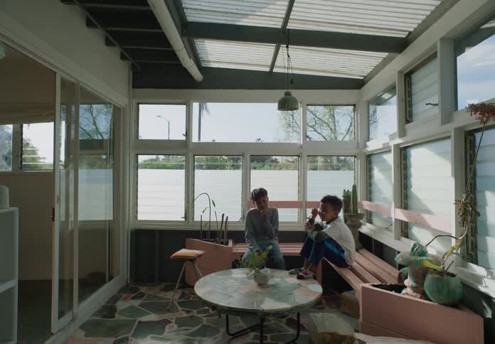 Two young boys sitting on a bench in a sun room while they talk