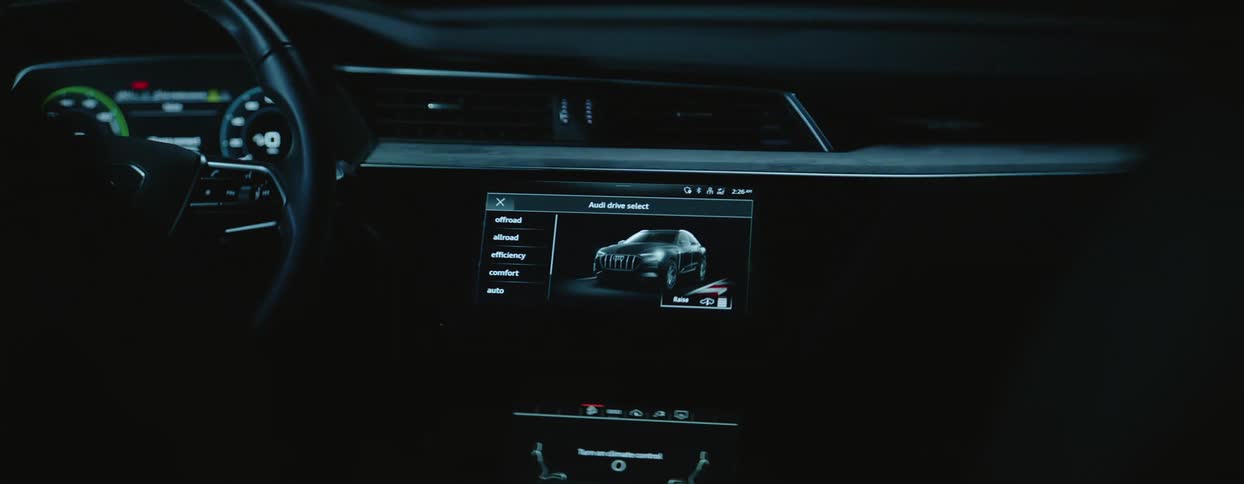 The interior of a car with a large screen interface on the dashboard as a person puts their hands on the wheel