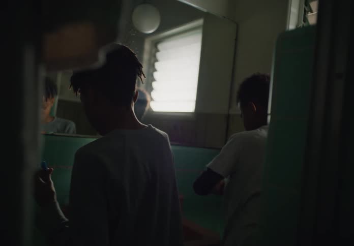 Two siblings walk in to bathroom and brush their teeth