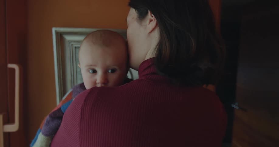 A mother holds her baby daughter and sways back and forth while standing