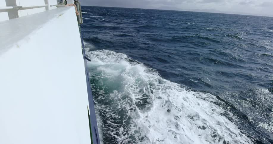 A boat is sailing in the water giving off waves as it travels