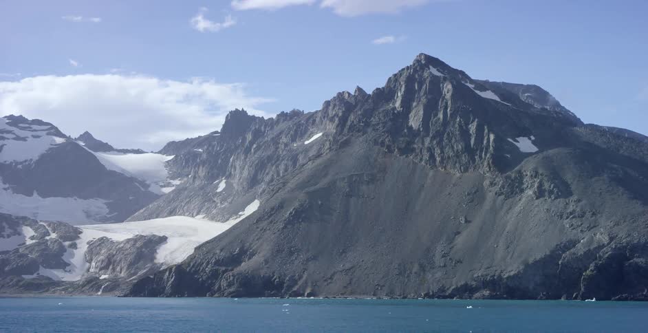 Steep mountains covered with glacial ice rise out of the ocean