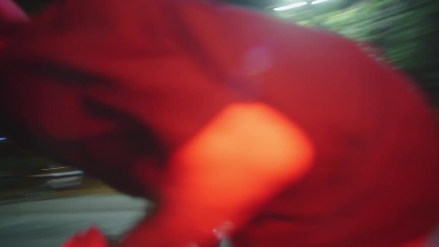 Young man riding around in circles on urban basketball court at nighttime