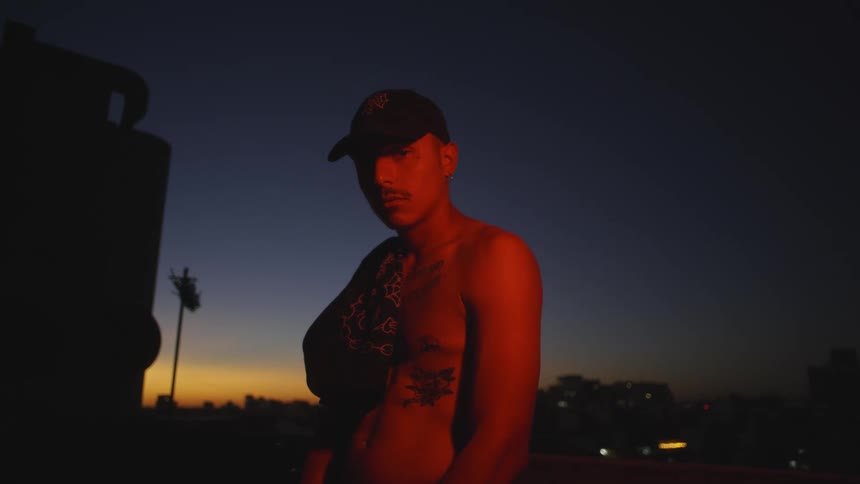 A man is shirtless at sunset with red light