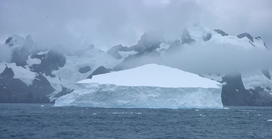 A large iceberg floats near a mountain