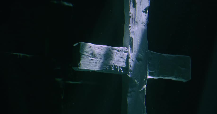 A white cross in the darkness has light repeatedly pass over it