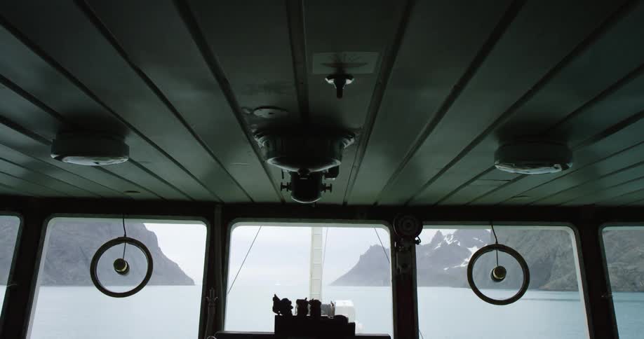 The windows inside a ship show mountains and water ahead