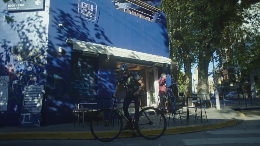 Man pulling up on his bicycle and stopping in front of a cafe