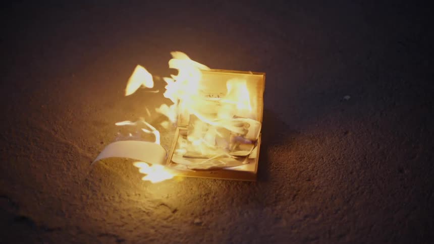 A small box of photos burns in a parking lot