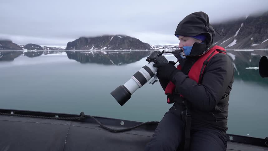 A person on a moving boat looking at the back of their camera