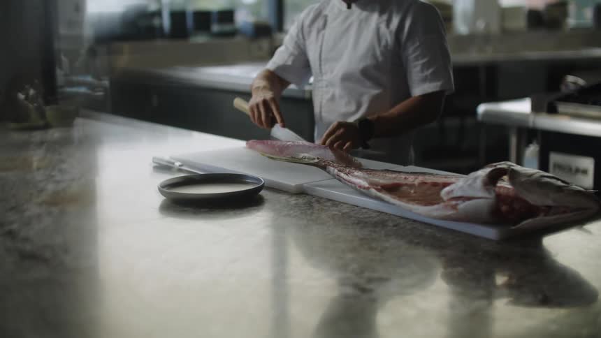 A chef is cutting a fish