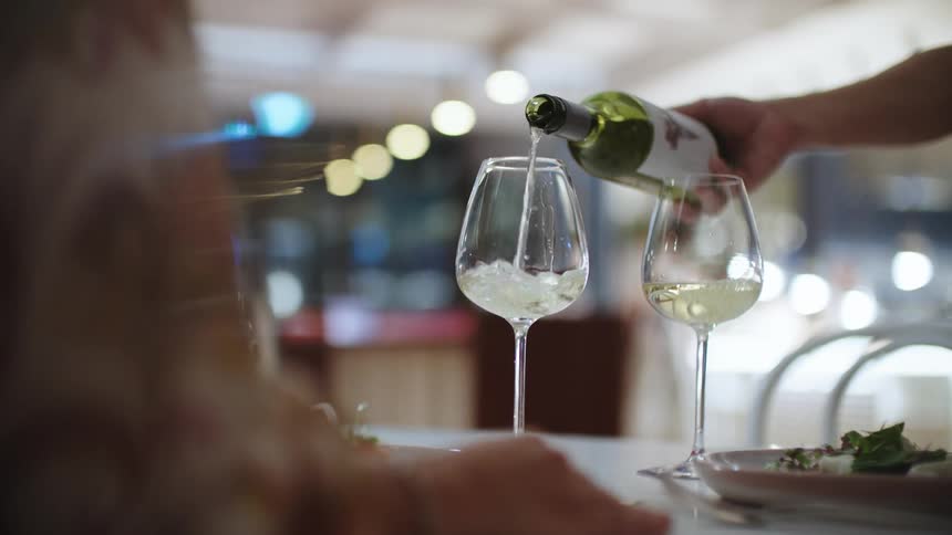 Server pouring wine wine in glasses at a restaurant