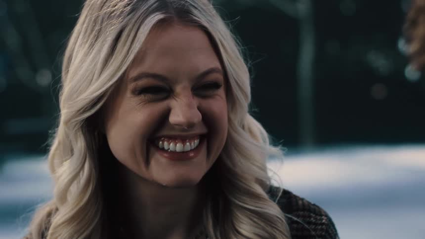 A woman is smiling and standing outdoors