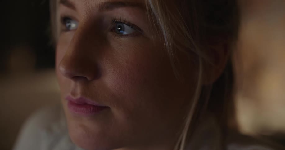A woman stands near a window at home