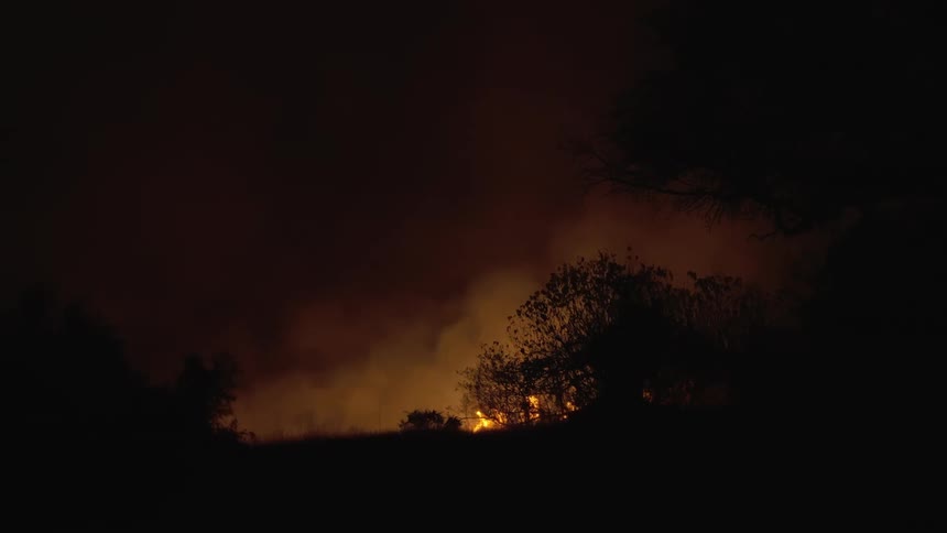 A fire can be seen burning in the distance as it releases smoke into the sky