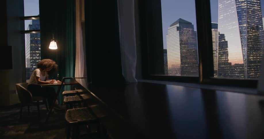 A woman sits alone in a office building while review documents at a desk