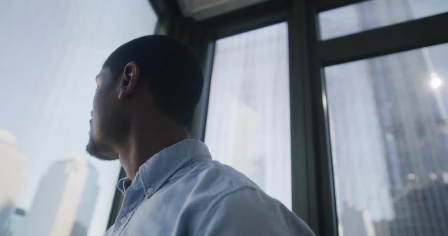 A man is looking at the city from his windows