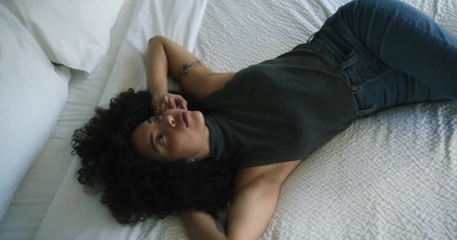 Young attractive woman with a big afro resting in the bed looking up