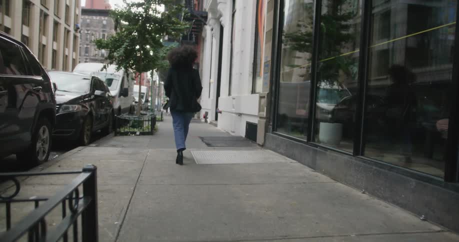 Pedestrians walk along sidewalk past rail enclosed trees