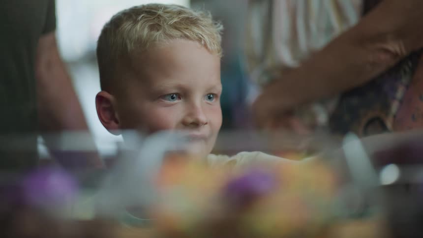 A boy points at desserts in a display case