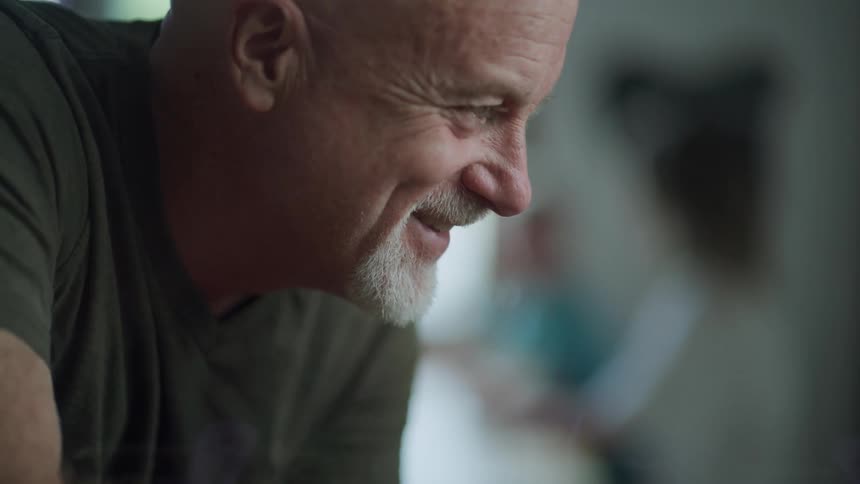 Happy bald man with a white beard goatee looks at his son while shopping
