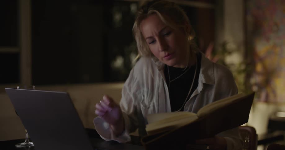 A woman is reading and typing on her laptop
