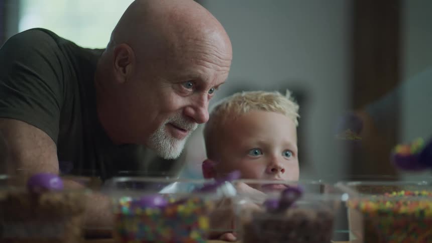 A man and a little boys face in front of a glass with candy in containers