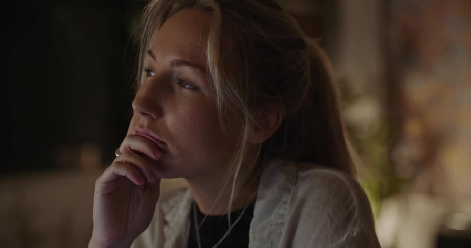 Woman sits in dimly lit room thinking before working