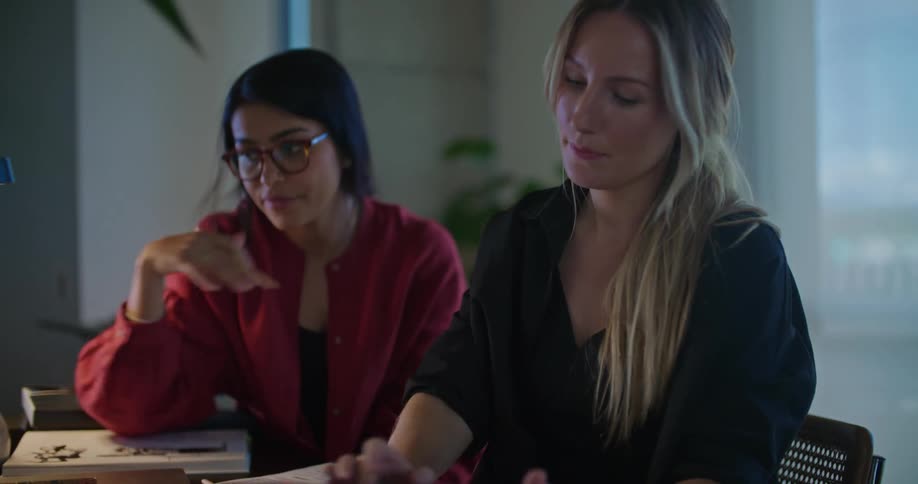 Two female coworkers have a lively conversation at the office