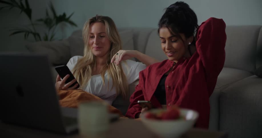 Two women talk while holding their phones