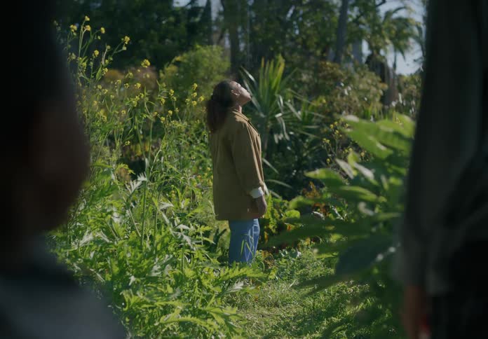 Woman standing on the overgrown vegetation in the backyard stands still for a moment
