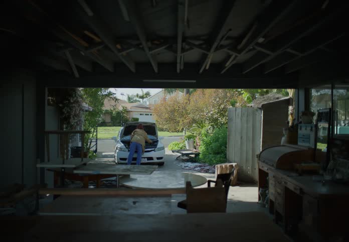A father checks on a vehicle as two boys run towards it