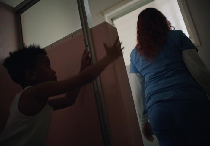 Woman sitting on the floor of a room with her son stands up to look out the window