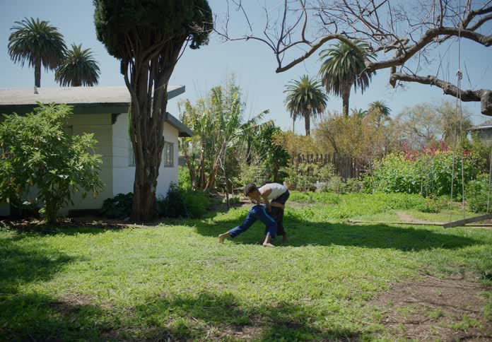 Two boys play wrestle in their backyard